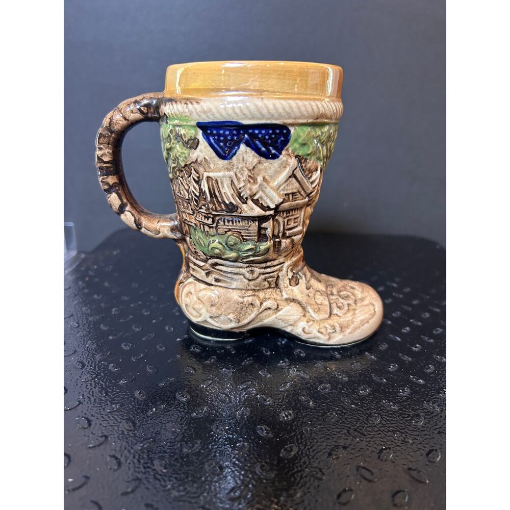 vintage ceramic boot-shaped mug featuring a raised relief scene of a village